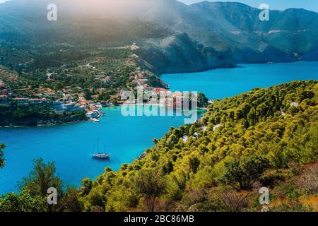 Panoramablick auf das Dorf Assos Kefalonia. Griechenland. Weiße einsame Yacht in wunderschönen türkisfarbenen Lagune Wasser von Pinien und Zypressen t umgeben Stockfoto