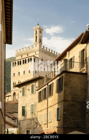 Gubbio, Mittelitalien. Von einer typischen engen Straße dieser Altstadt aus bietet sich ein eindrucksvoller Blick auf die Architektur dieser Stadt mit dem 'Palazzo dei Consoli'. Stockfoto