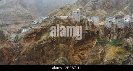 Siedlung an der felsigen Küste der Insel Santo Antao. Häuser schmiegen sich in die Felswand des Blauen Kamms. Dorf Fontaihas. Stockfoto