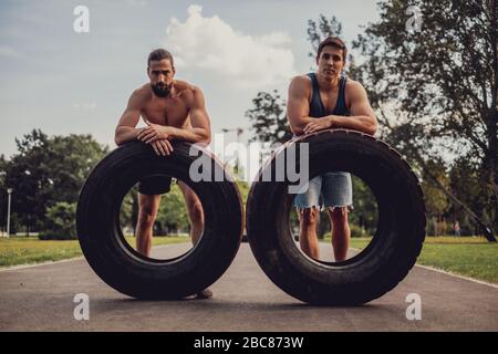 Männliche Athleten ruhen sich von einem Training mit Reifen im Park aus Stockfoto