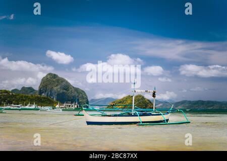 Traditionelle banca-fischer booten in der flachen Lagune am Strand von Corong. Nido, Philippinen. Blauer Himmel und Wolken über dem Bacuit Archipel. Stockfoto