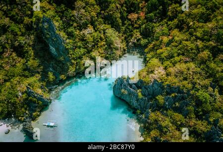 Antenne drone Blick auf blau türkis transparent Lagoon Water der tropischen Insel mit schroffen Felsen, steilen Berge, Dschungel und Sandstränden. Stockfoto