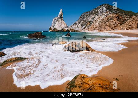 Portugal Ursa Beach an der atlantikküste. Schäumende Welle am Sandstrand mit surreal anmutendem Felsen in malerischem Landschaftshintergrund an der Küste. Stockfoto