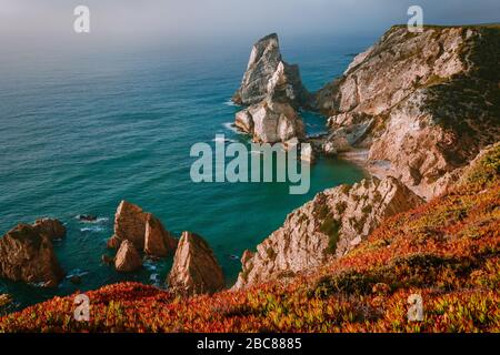 Surreale und bizarre Felsen am Strand Praia da Ursa, Sintra, Portugal am Abend goldenes Feuer Sonnenuntergang Licht. Atlantikküste in der Nähe des berühmten Cabo da Ro Stockfoto