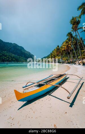 Traditionelle hölzerne banca Boot auf schöne Las Cabanas am Strand. Sommer Urlaub, Insel Hopping, El Nido, Magie der Philippinen. Stockfoto