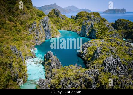 El Nido, Palawan, Philippinen. Antenne drone Ansicht von schönen großen Lagune von Karst Kalkstein Klippen umgeben. Touristen entdecken Bereich auf Kajaks. Stockfoto