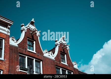 Nahaufnahme der alten Gebäudefassade und Dachschmuck gegen den blauen Himmel in Amsterdam. Architektonische Details Nordholländer. Stockfoto