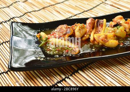 Gegrillter Tintenfisch, der würzige Sauce auf dem Teller anzaugt Stockfoto