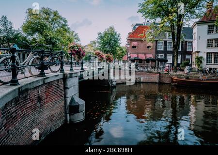 Herbstliche Amsterdamer Kanalszene mit Fahrrädern und Brücke. Stockfoto