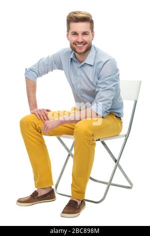 Junger Mann auf einem Stuhl sitzend Stockfoto