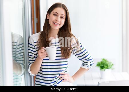 Frau beim Entspannen mit einer Tasse Kaffee auf ihrem Balkon Stockfoto