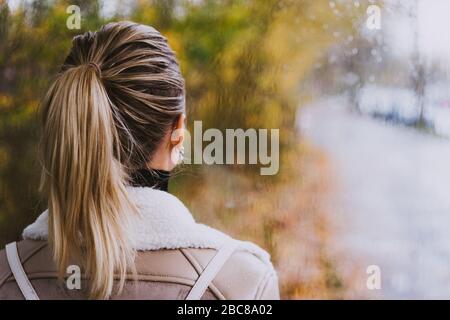 Nachdenkliche Frau, die durch das Fenster blickt. Rainly Street, goldener Herbst Stockfoto