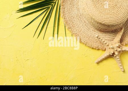 Strohhut, Palmzweig und Seesterne auf gelbem Hintergrund, Draufsicht Stockfoto