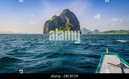 Banca Boot nähert sich riesig Rocky Island am windigen Tag, El Nido, Palawan, Philippinen Stockfoto