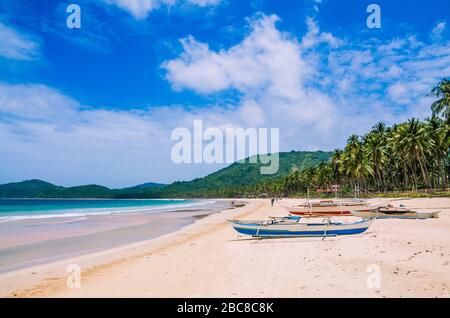 Lokale Boote an breiten Nacpan Strand an sonnigen Tag. El Nido, Palawan, Philippinen. Stockfoto