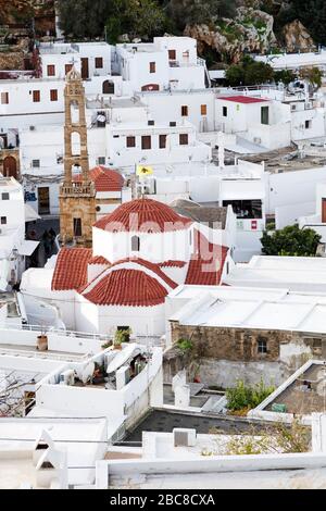 Weiße Häuser in Lindos auf Rhodos, Griechenland. Über Gebäuden in der Stadt erhebt sich die Panagia-Kirche. Stockfoto