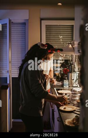 Glückliches Paar bereitet Pfannkuchen in der Küche am Silvesterabend Stockfoto