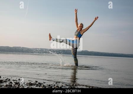 IKYA-Meditation, Frau in Sportswear fröhlich am See Stockfoto