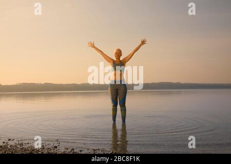 IKYA-Meditation, Frau in Sportswear fröhlich am See Stockfoto