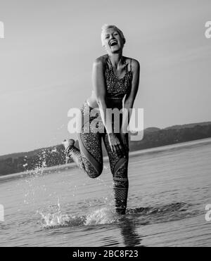 IKYA-Meditation, Frau in Sportswear fröhlich am See Stockfoto