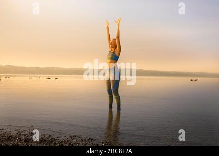 IKYA-Meditation, Frau in Sportswear fröhlich am See Stockfoto