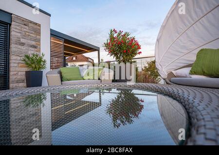 Loungemöbel auf einer modernen Terrasse mit Spiegelung in Glastisch Stockfoto