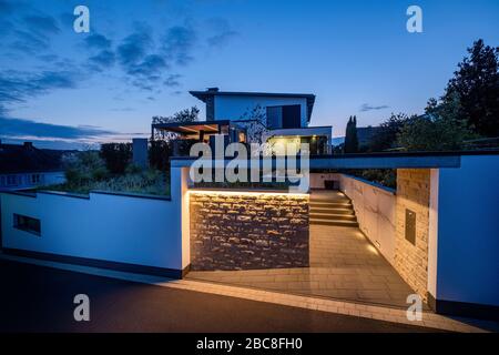 Hauseingang mit Zufahrtsweg und Treppe in der Nacht mit stimmungsvollem Lichtkonzept Stockfoto