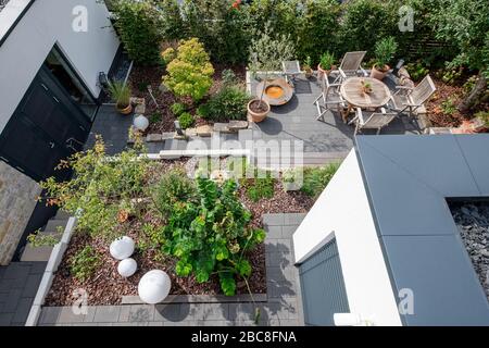 Überblick über eine gepflegte Gartenlandschaft mit Terrasse, Pflanzenbeeten und Zufahrtswegen Stockfoto