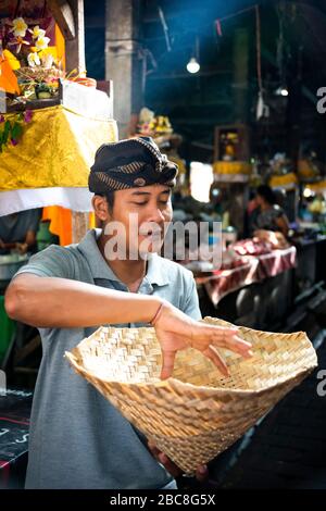 Vertikaler Portait eines Mannes, der einen traditionellen Reisdampfer in Bali, Indonesien, hält. Stockfoto