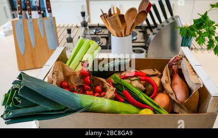 Lokale Lieferung von frischem Gemüse an der Küchenecke: Sellerie, Kirschtomaten, Lauch, Zwiebeln, Kartoffeln, rote Chilis, Frühlingszwiebeln & Limes Stockfoto