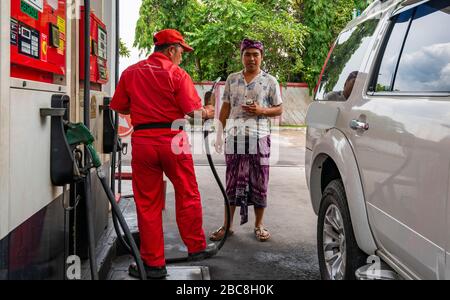 Horizontaler Blick auf einen Mann, der sein Auto in Bali, Indonesien, mit Benzin gefüllt hat. Stockfoto