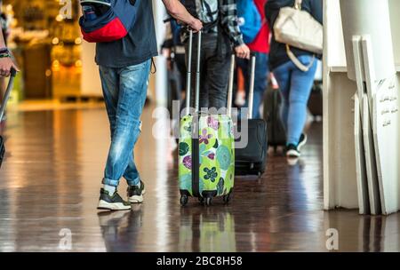 Reisende mit Koffern, die durch den Flughafen laufen. Nahaufnahme der Beine von Passagieren, die mit Koffer in den Flughafen gehen Stockfoto