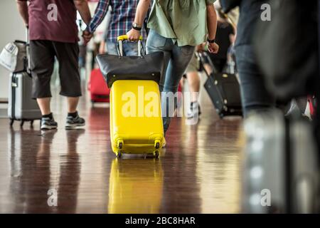 Reisende mit Koffern, die durch den Flughafen laufen. Nahaufnahme der Beine von Passagieren, die mit Koffer in den Flughafen gehen Stockfoto