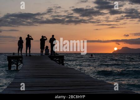 Spanien, Mallorca, Playa de Muro, Touristen fotografieren Sonnenaufgang von einem Anlegesteg am Playa de Muro, dem längsten Sandstrände Mallorcas Stockfoto