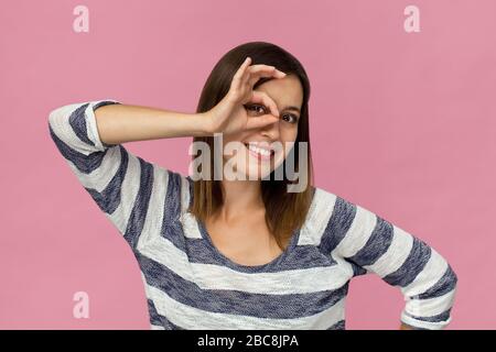 Fröhliche junge Brunette-Frau mit elegantem Hemd lächelndes Porträt vor pinkfarbenem Hintergrund. Lustige Geste Stockfoto