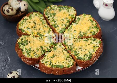 Hausgemachte heiße Sandwiches mit grünen Zwiebeln, ramson Wildblauch, Wachteleiern, Käse und Petersilie auf dunklem Hintergrund, selektive Fokussierung Stockfoto
