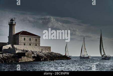 Segelboote treten bei Sonnenuntergang, Segelrennen, Spiegelung der Segel auf dem Wasser, mehrfarbige Spinnaker, Bootsnummer Achterboote, Big an Stockfoto