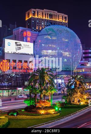 Shanghai, Xuhui, China - 3. Mai 2010: Nachtportraitfoto von farbenfroh beleuchteten Halbglobus mit mehrstufigen Fassadenabdeckungen von Einkaufszentrum und Hochhaus Stockfoto