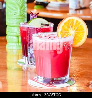 Flug von traditionellen mexikanischen alkoholischen Getränken auf hell glänzenden Holzfläche in traditionellen mexikanischen Restaurant mit orangefarbenen Scheiben rosa rot grünen Getränken Stockfoto