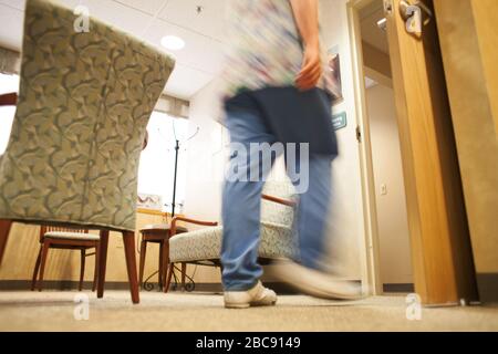 Eine Krankenschwester läuft über den Warteraum eines Krankenhauses. Stockfoto