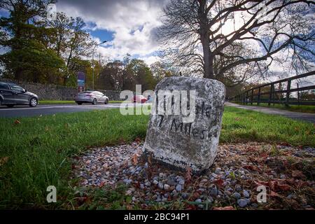 Adare, County Limerick, Irland - 10/26/2018: Alte Steinmarkierung am Straßenrand, die 7 Meilen bis Rathkeale auf der N21 bei Blackabbey zeigt. Stockfoto