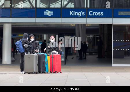 London, Großbritannien. April 2020. Eine Gruppe ausländischer Reisender mit Rollgepäck verlässt den Bahnhof London King's Cross mit Schutzhandschuhen und Gesichtsmasken. Insgesamt 3.605 Menschen sind nun während der Pandemie an Covid-19-Coronavirus in ganz Großbritannien gestorben. Kredit: Thamesfleet/Alamy Live News Stockfoto