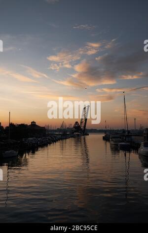 Wunderschöner Sonnenaufgang über dem Black River im Stadtzentrum von Port huron, Michigan mit Blick auf den Jachthafen und die Zugbrücke. Stockfoto