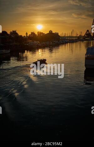 Einzelboot bei Sonnenaufgang, der Black River in Port Huron, MI zum St. Clair River und Lake Huron fährt. Stockfoto