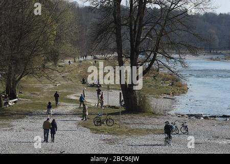 München, Deutschland. April 2020. Spaziergänger gehen bei strahlendem Sonnenschein am Isarufer in der Nähe des Zoos Hellabrunn entlang. Kredit: Felix Hörhager / dpa / Alamy Live News Stockfoto