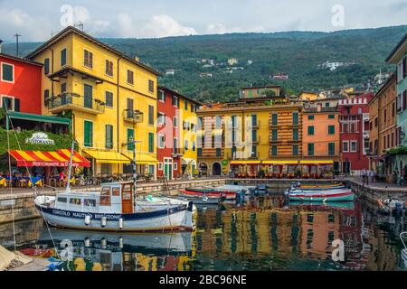 Gardasee mit Häusern, Touristen und Booten in Torbole, Italien Stockfoto