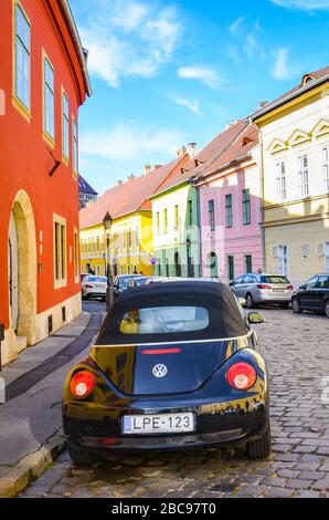 Budapest, Ungarn - 6. November 2019: Schöne historische Straße mit bunten Häusern im historischen Zentrum. Geparkte Autos auf der gepflasterten Straße. Altstadt der ungarischen Hauptstadt. Bunte Fassaden. Stockfoto