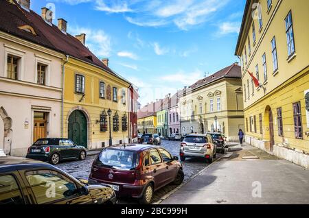 Budapest, Ungarn - 6. November 2019: Schöne historische Straße mit bunten Häusern im historischen Zentrum. Geparkte Autos auf der gepflasterten Straße. Altstadt der ungarischen Hauptstadt. Horizontales Foto. Stockfoto