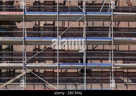 Vorderansicht der Gerüste vor dem alten historischen Gebäude mit schönen Ziegel dekorative Fassade und Fenster auf der renovierten Baustelle. Stockfoto