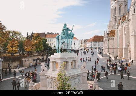 Budapest, Ungarn - 6. November 2019: St. Stephen Reiterstandbild von hinten. Touristen, die auf dem Platz an der Fischerbastion in der ungarischen Hauptstadt besichtigen. Matthias Kirche im Hintergrund. Stockfoto